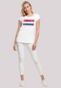 White short-sleeve T-shirt featuring red and blue horizontal stripes. Paired with white skinny pants and white sneakers, smooth fabric texture.
