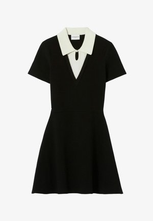 Vestido negro con mangas cortas, escote en V, cuello blanco y un detalle de ojal en el cuello. Falda acampanada, hecha de un tejido texturizado.