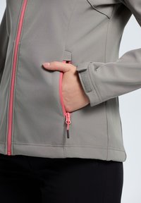 Light gray softshell jacket with a pink front zipper and side pocket. Features a streamlined design and adjustable cuffs.