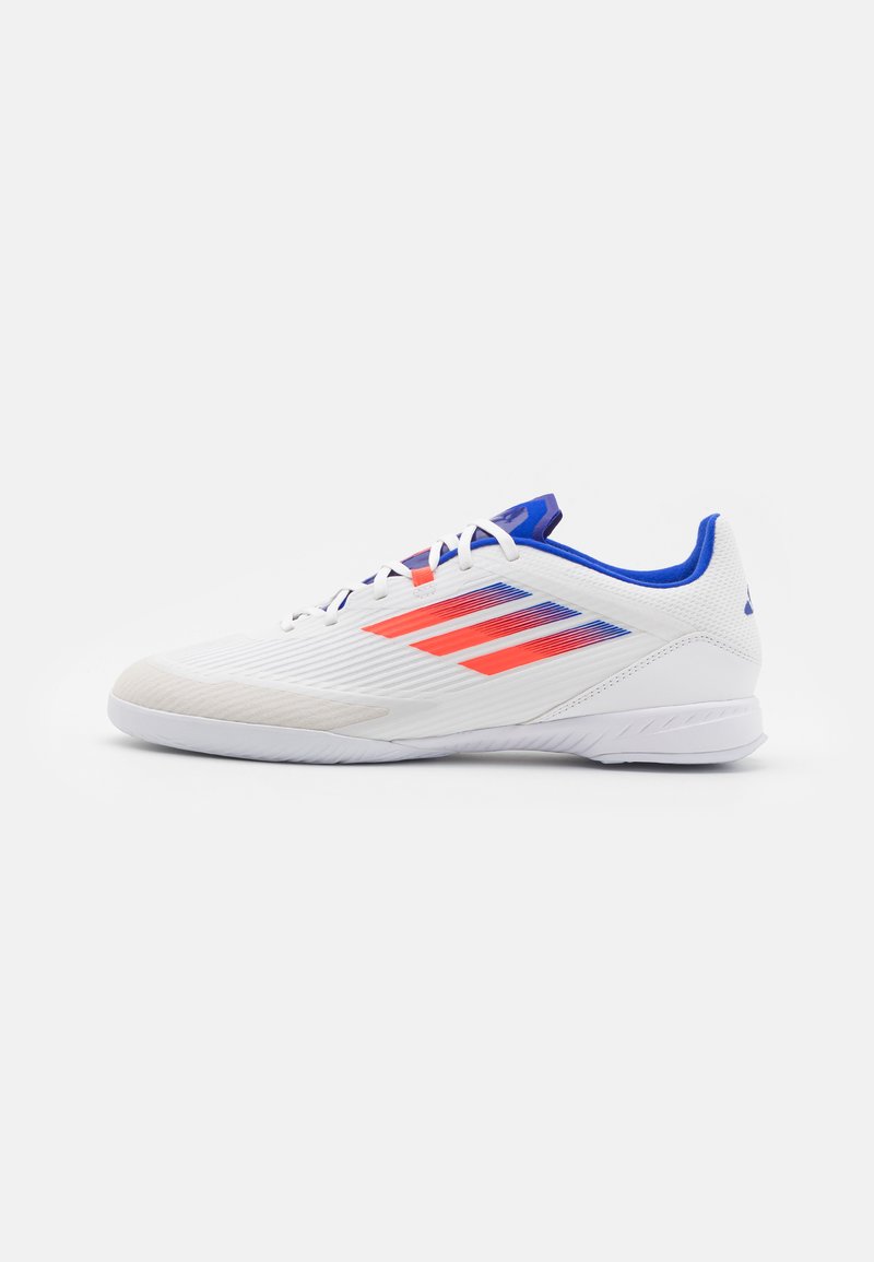 White athletic shoe with textured upper, red and blue stripes, rounded toe, and a cushioned sole. Lightweight design for performance.