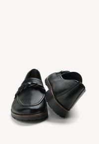 Zwarte leren schoenen met een ronde neus, gevlochten details aan de voorkant, gestructureerde oppervlakken en een lage rubberen zool.