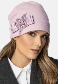 Beanie roz din lână, cu accente de panglică florală, prezentând două trandafiri din material și perle decorative. Textură moale, design ajustat și aspect călduros.