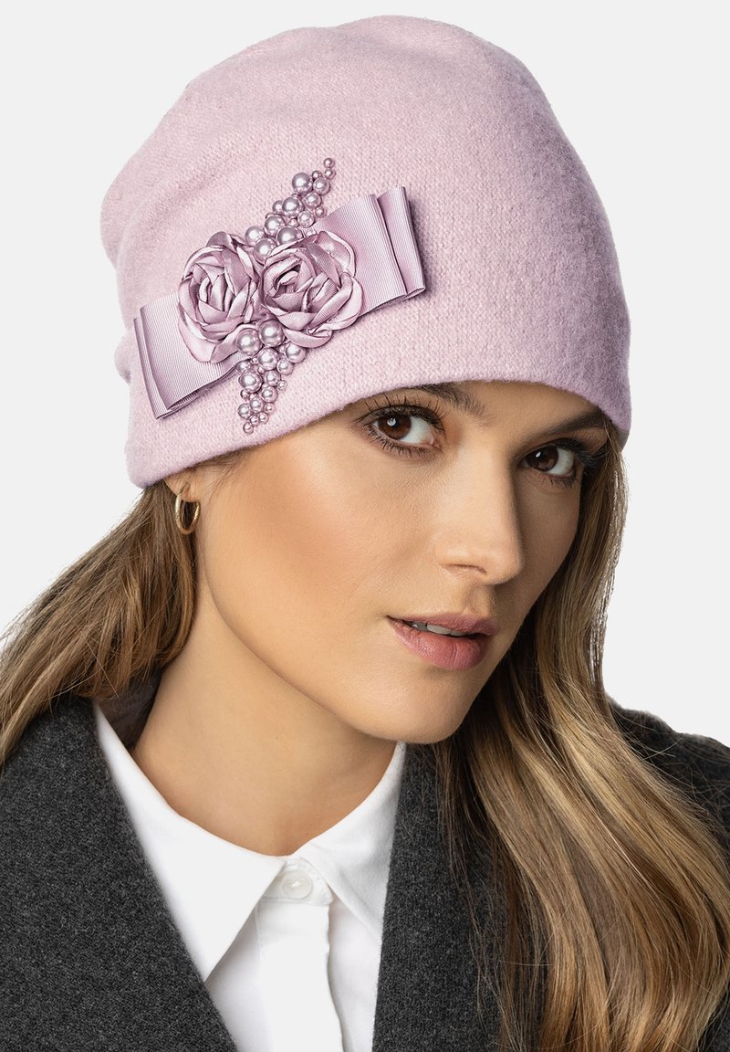 Beanie roz din lână, cu accente de panglică florală, prezentând două trandafiri din material și perle decorative. Textură moale, design ajustat și aspect călduros.