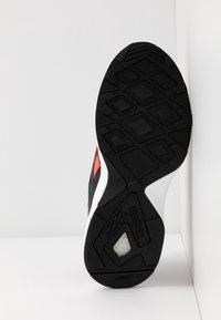 Czarna sportowa podeszwa buta z gumowym bieżnikiem, biała środkowa część podeszwy i kolorowe akcenty w czerwonym i niebieskim. Posiada szczegółowy wzór heksagonalny.