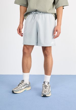 Shorts de sport bleu clair en tissu texturé, avec une taille élastique et un cordon de serrage externe. Présente un petit logo Nike blanc.