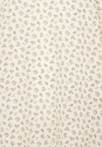 Tecido com padrão floral, apresentando pequenas flores roxas e amarelas sobre um fundo crema. Textura suave com um design leve.