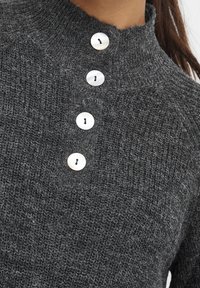 Dunkelgrauer Strickpullover mit hohem Kragen und vier weißen Knöpfen in der Mitte vorne.