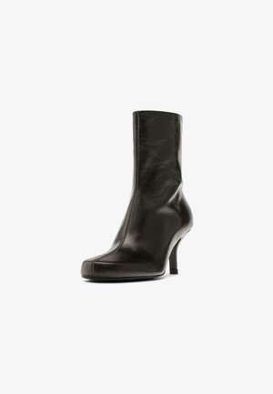 Stivaletto in pelle nera con una vestibilità aderente, punta appuntita e un tacco a stiletto sottile. Presenta una texture liscia e dettagli di cucitura sottili.