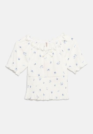 Blouse blanche à épaules dénudées avec imprimé floral bleu, manches courtes bouffantes, encolure à volants, détail noué et ourlet smocké à volants.