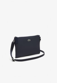 Sac bandoulière bleu marine texturé avec fermeture éclair. Comprend un accent logo et une sangle amovible avec une finition lisse. Design compact.