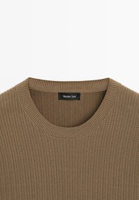 Brun ribstrikket crewneck-trøje med et sort "Massimo Dutti"-mærke syet ind i kraven.