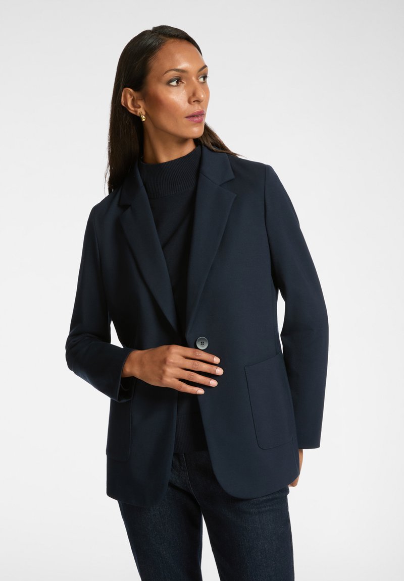 Blazer tailored blu navy con chiusura a bottone singolo, revers a notched e due tasche frontali; realizzato in un tessuto liscio e strutturato.