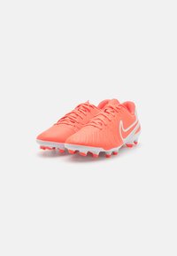 Nike football boots in bright neon pink with textured upper, white accents, and molded studs for traction on grass surfaces.