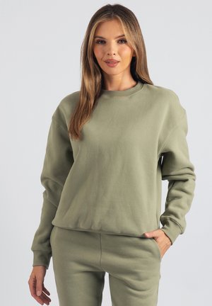 Bluza w kolorze oliwkowej zieleni z miękkiej, szczotkowanej bawełny, z okrągłym dekoltem, opuszczonymi ramionami, ściągaczami na rękawach i luźnym krojem. Miękkie, teksturowane wykończenie.