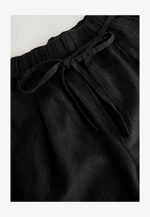 Schwarze Leinenhose mit elastischem Bund, ausgestattet mit einer Bindeschließe und weichem Material, das dezente Falten und Fältchen zeigt.