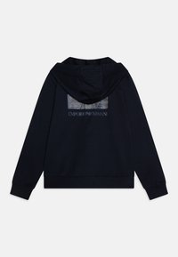Felpa navy con zip, con una patch logo sul retro. Realizzata in materiale morbido, con maniche lunghe e un cappuccio spazioso.
