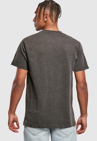 Camiseta de algodón gris oscuro de manga corta, con cuello redondo y un corte relajado, mostrada desde la parte de atrás. Textura suave y costuras mínimas.
