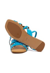 Blaue Ledersandalen mit überkreuzten Riemen, flacher Sohle und einem glatten, braunen Fußbett. Größe 38 auf der Unterseite markiert.