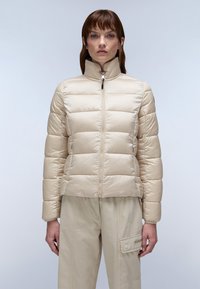 Beige gewatteerde jas met een hoge kraag, ritssluiting aan de voorkant en een horizontaal gestikt patroon. Draag het over lichte beige broek met een zak.
