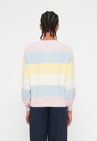 Maglione lavorato a maglia in colori pastello: strisce rosa, blu, giallo e crema. Presenta una vestibilità rilassata e polsini a costine. Texture liscia.