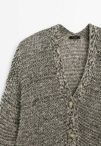 Cardigan gris et blanc en maille, avec un col en V, deux boutons beiges et un motif tissé texturé.