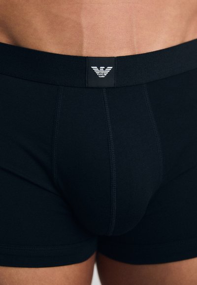 Boxer shorts noirs en tissu stretch avec une taille de marque et un logo contrastant, texture lisse et coupe ajustée.
