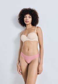 Beige gepolsterter BH mit dünnen Trägern und nahtlosem Design, kombiniert mit hellrosa tief sitzenden Unterhosen, beide aus glattem Material.