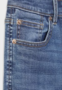 Modre jeans hlače iz jeansa z žepom spredaj in majhnim žepkom za kovance, z bakrenimi zakovicami in oranžnimi šivi.