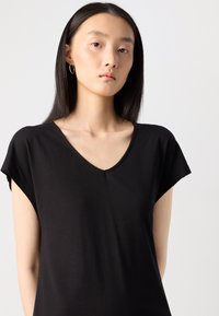 Black V-neck top with short sleeves, made of soft, lightweight fabric. Features a relaxed fit and smooth texture for comfort.