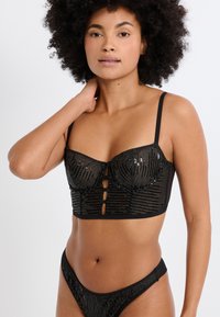 Schwarzes, mit Pailletten besetztes Bralette mit strukturierter Körbchenform, vertikalen Streifen, verstellbaren Trägern und drei vorderen Knopfverschlüssen.