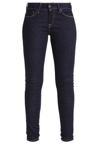Jeans ajustados de mezclilla de color azul oscuro, que presentan un diseño clásico de cinco bolsillos, costuras amarillas y un cierre frontal con botón.