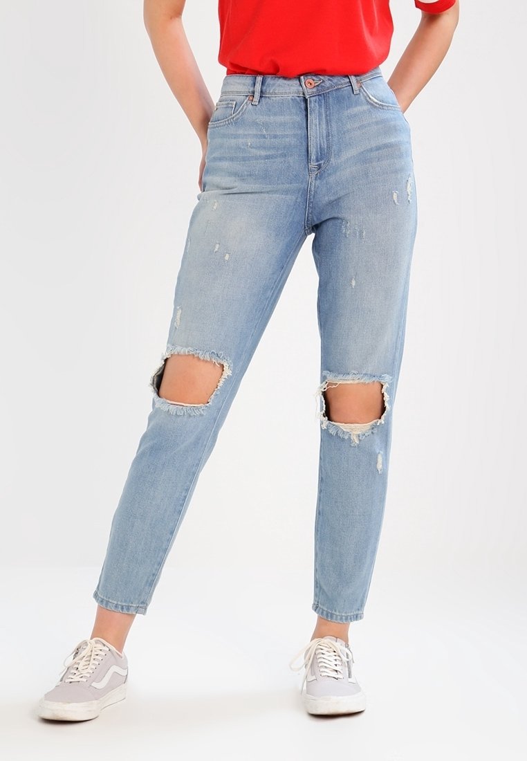 Blå denimjeans med slitna detaljer, inklusive två stora knäutsparningar. Den högmidjade designen har en klassisk femfickorsstil.