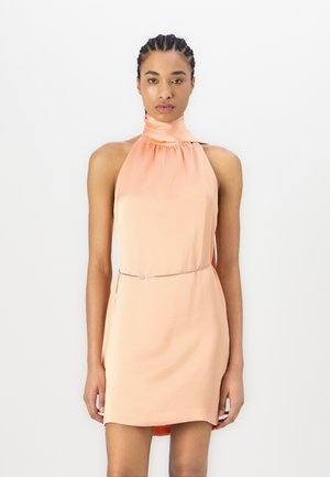 Halter neck dress in soft peach fabric, features a gathered collar, slim silhouette, and a thin silver belt accented with a small clasp.