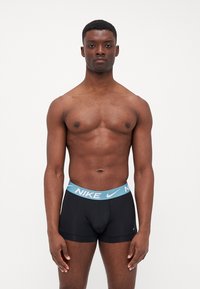 Boxeri atletici negri cu un brâu elastic de culoare bleu deschis, având logo-ul Nike. Materialul pare neted și ajustat.
