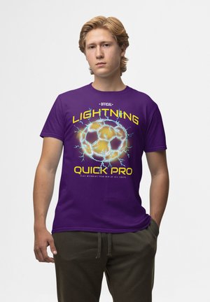 Lilla bomulds t-shirt med et fodbold grafik og lyn accenter. Teksten inkluderer "OFFICIEL LIGHTNING QUICK PRO" i gul og blå.