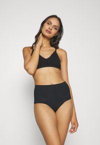 Fekete vezeték nélküli bralette csipke díszítéssel és magas derekú fekete fehérnemű, mindkettő puha szövetből készült, sima tapintással és minimalista dizájnnal.