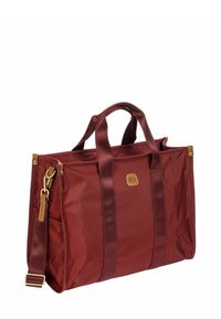 Borsa tote in nylon rosso con due manici superiori, tracolla staccabile, hardware dorato e una tasca laterale. Presenta una patch in pelle con il logo.