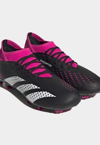 Mustat ja vaaleanpunaiset jalkapallositeit featuring tekstuurinen synteettinen päällinen, valkoiset korostusraidat ja matala profiili optimaalista suorituskykyä varten.