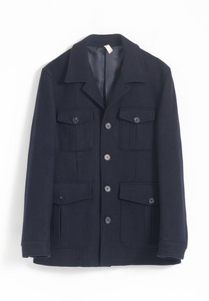 Chaqueta azul marino de lana, con cuello, seis bolsillos delanteros y cierre de botones. Textura suave, con interior forrado.