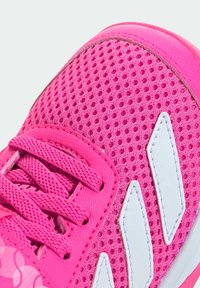 Růžová sportovní bota s síťovaným svrškem, bílými akcenty a texturovanými tkaničkami. Design zahrnuje zesílenou špičku a polstrovaný límec.