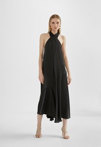 Black halter dress in flowing satin fabric with an asymmetrical hem. Features a simple, elegant design and minimal embellishments.