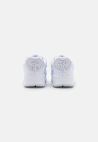 Baskets blanches Nike Air avec une tige en cuir lisse, un col rembourré et un logo embossé sur le talon. Semelle extérieure en caoutchouc avec une adhérence texturée.