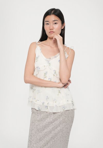 Bluză fără mâneci dintr-o țesătură ușoară și transparentă, cu straturi volănașe. Culori pastelate delicate de albastru și alb, cu flori fine și curele cu nod.