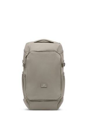 Rechteckiger beiger Rucksack mit Fronttasche, seitlichen Gurten, oberem Tragegriff und Johnny Urban Logo-Patch in der Mitte des Frontpanels.