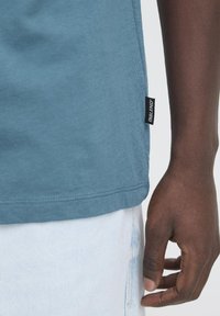 Blå bomuldstrøje med en glat tekstur, der har en sidelabel og en afslappet pasform, parret med lysefarvede denim.