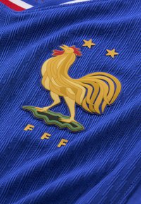 Jersey texturizado azul con un emblema de gallo dorado sobre un fondo verde, con dos estrellas amarillas arriba y las letras "FFF" abajo.