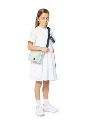 Robe blanche à manches courtes avec un motif subtil, assortie à un sac bandoulière argenté et des baskets blanches. Présente une sangle et des détails en marine.
