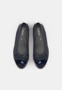 Marineblaue Stoff-Ballerinas mit einer glänzenden Lackeinstiegsfläche, einem Schleifenakzent und einem grauen Innenfutter. Runde Form, flexibles Design.