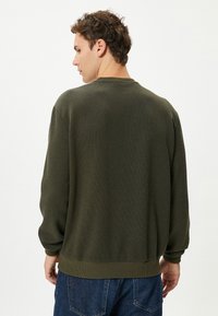 Groene geribbelde sweatshirt met lange mouwen, ronde hals en elastische zoom. De gestructureerde stof geeft diepte aan het algehele ontwerp.