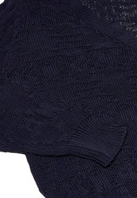 Maglione lavorato a maglia blu navy con motivi testurizzati, polsini a costine e una vestibilità ampia. Il tessuto appare morbido e leggero con una finitura liscia.